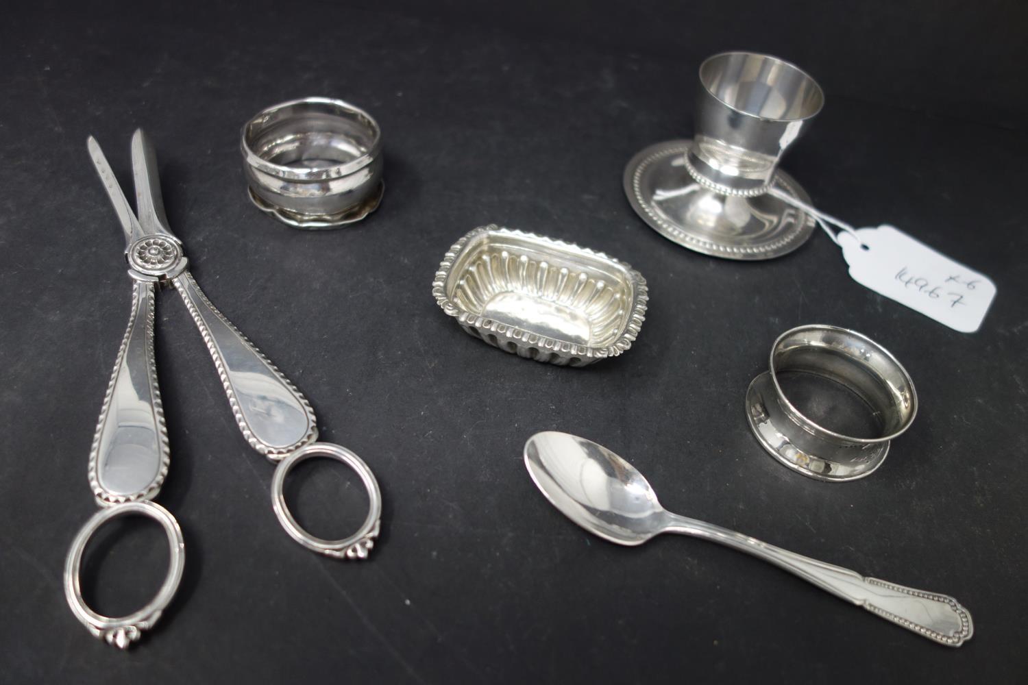 A collection of silver, to include two napkin rings, a teaspoon, a small gadrooned dish, and an