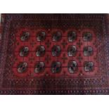 A Northeast Persian Turkoman rug, repeating stylised Tekkeh motifs on a rouge field, complimented by