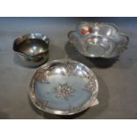 Three Greek white metal bowls, to include one with planished center and floral decoration, on
