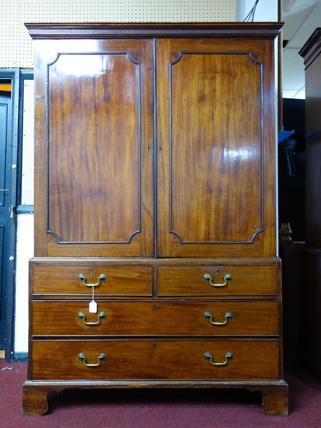 A late 18th century mahogany linen press, with 2 doors enclosing linen trays, above drawers,