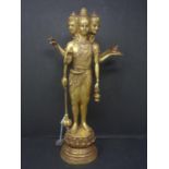 A gilt bronze figure of a deity with three heads and six arms, on circular stepped base, H.37cm