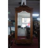 An early 20th century French walnut armoire, with carved crest and bevelled mirrored door, H.238 W.