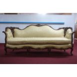 An early 20th century walnut bergere sofa, with floral carving, on cabriole legs and scroll feet,