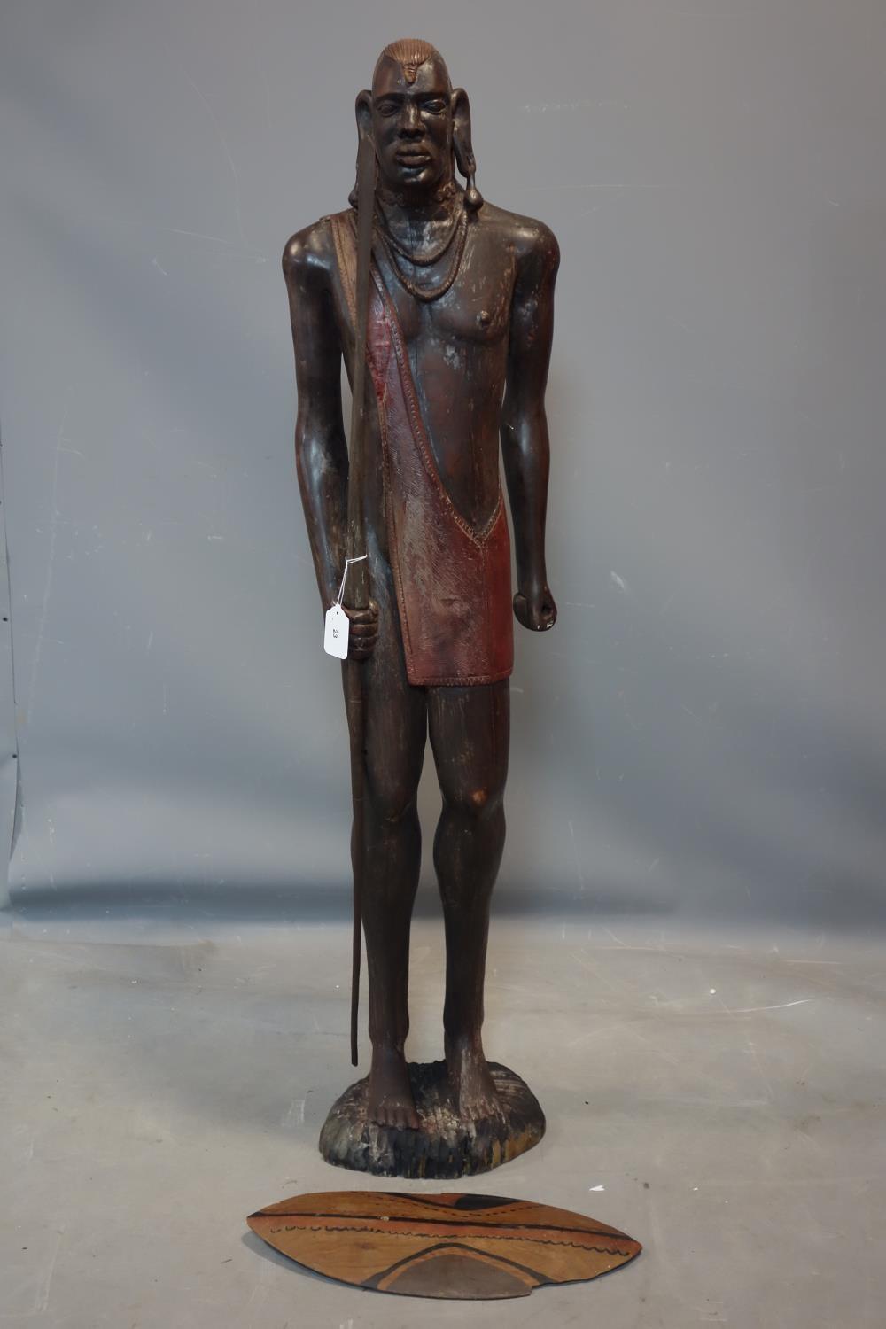An African wooden carving of a Maasai warrior, carrying wooden spear and with shield (shield