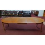 A 20th century teak extending dining table, with 3 extra leaves, raised on tapered legs, H.73 W.