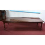 A Victorian style mahogany wind out dining table, raised on turned reeded legs and castors, with 3