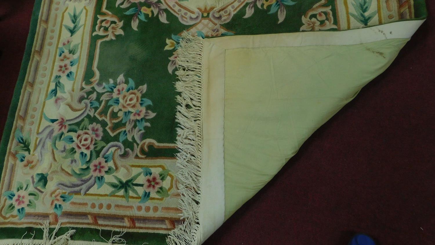 A large ornate Chinese rug with emerald central floral design on a green ground and cream border. - Image 2 of 2