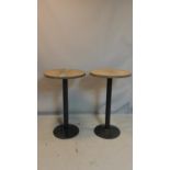 A pair of tall pub tables with circular oak tops, raised on black steel bases, H.98 D.60cm