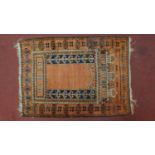 A Persian prayer rug with stylised motifs on an orange field within geometric borders, 140cm x 100cm
