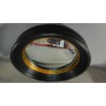 A Regency style ebonised framed convex mirror with gilt slip. 64x64cm