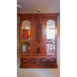 An Edwardian mahogany and inlaid wardrobe, mirrored doors enclosing twin hanging sections, fitted