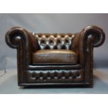 A brown leather Chesterfield club armchair on castors