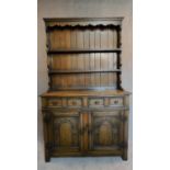 A Jacobean style Ipswich oak dresser with plate rack above drawers and carved cupboard doors. H.