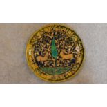 A Persian glazed ceramic plate, decorated deer amid naturalistic setting, dated and marked to
