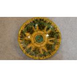 A Persian glazed ceramic dish in green and ochre, dated and marked to base. 6x27