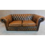 A two seater brown leather chesterfield sofa. H.68 W.163 D.84cm