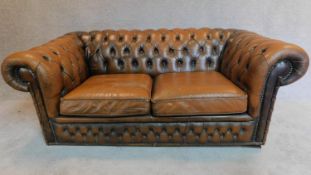 A two seater brown leather chesterfield sofa. H.68 W.163 D.84cm