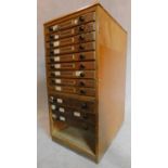 A 1930/40's oak collectors cabinet with inset glass top, above 12 drawers, raised on plinth base,