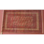 A Persian meshad belouch rug, repeating stylised geometric motifs on a red field within multi