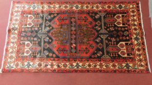 A Persian Nahawand rug, central medallion with repeating petal motifs on midnight field within multi