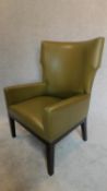 A contemporary designer green leather wing back armchair, raised on ebonized legs, with makers stamp