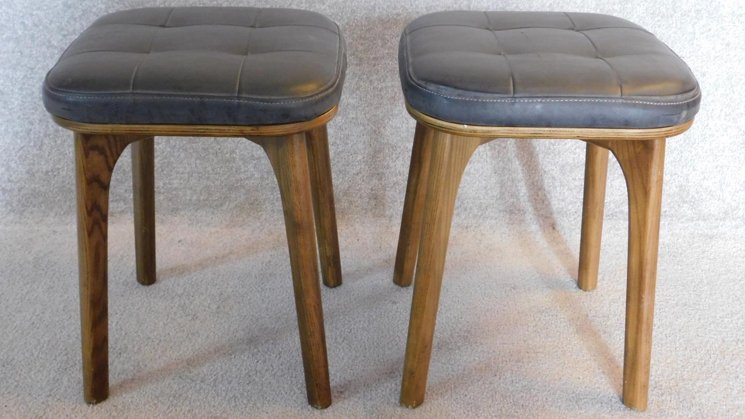 A pair of vintage 1970's ash stools upholstered in buttoned charcoal leather. 47x37x37cm