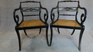 A pair of Regency ebonized scroll armchairs, with caned seats and gilt metal mounts, raised on sabre