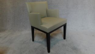 A contemporary designer grey leather armchair, raised on ebonized legs, with makers stamp to frame