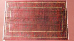 A Persian Hatchlie rug, repeating geometric motifs on rouge field. 219x100cm.