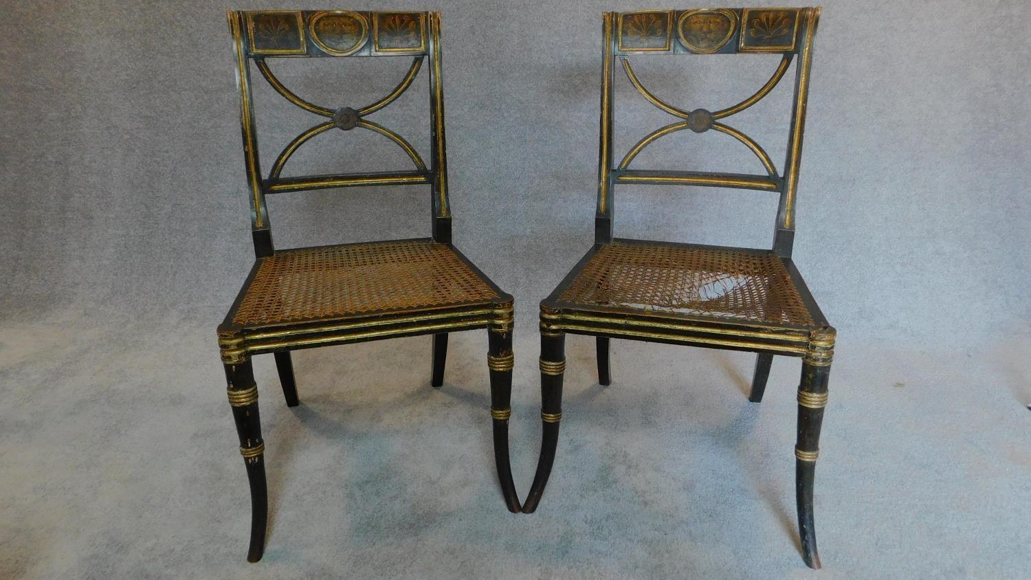 A pair of Regency ebonized and part gilt painted chairs with cane seats, the X-framed back rests