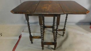 A mid 20th century oak drop flap dining table. H.75 W.93 D.59cm (top split and worn)