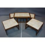 A 20th century teak nest of table with tiled tops, together with a pair of matching coffee tables