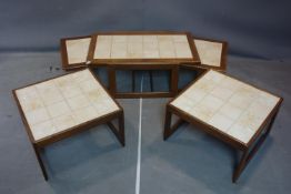 A 20th century teak nest of table with tiled tops, together with a pair of matching coffee tables