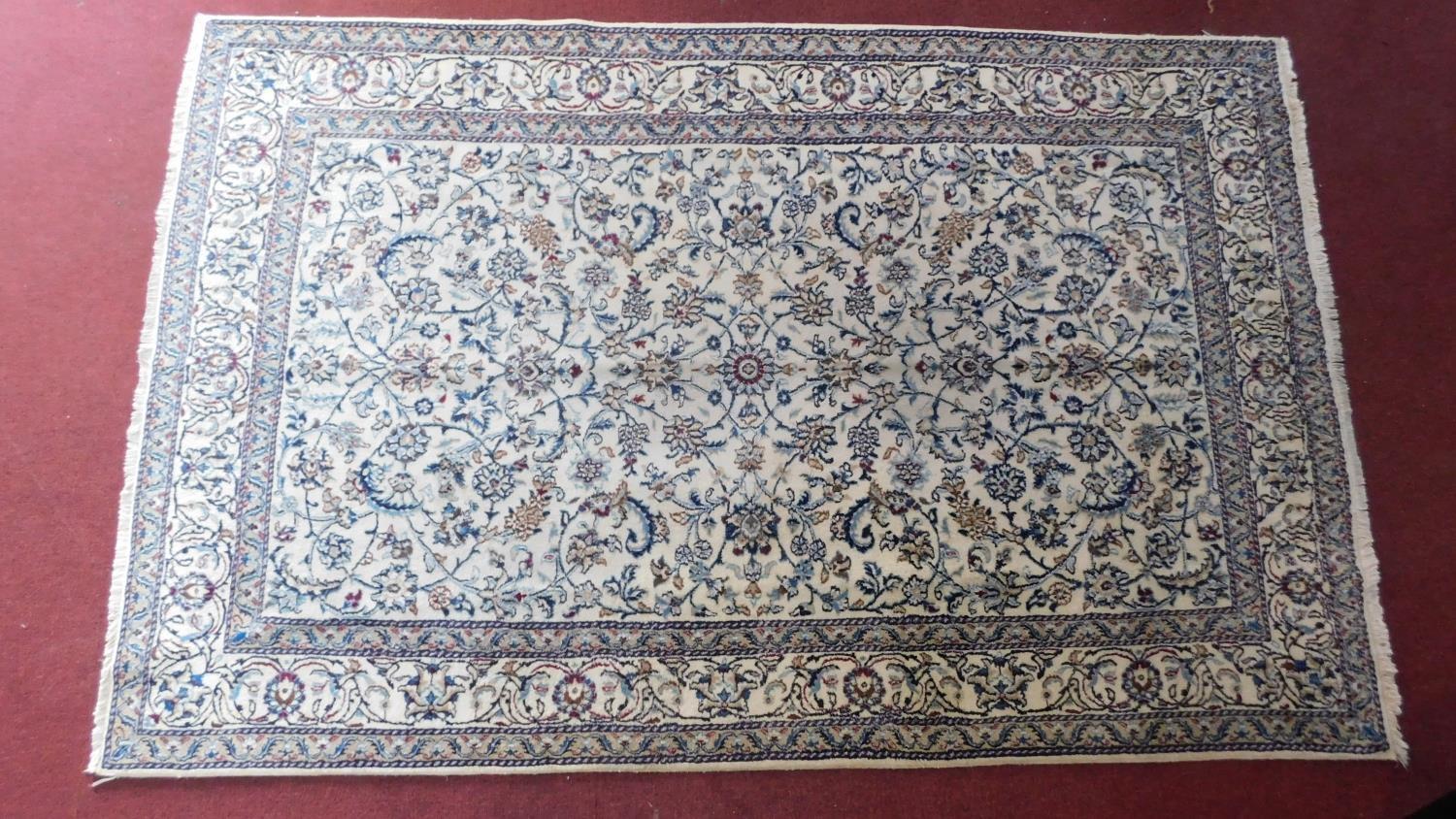 A part silk Nain Isfahan carpet with repeating spandrels and petal motifs on an ivory field