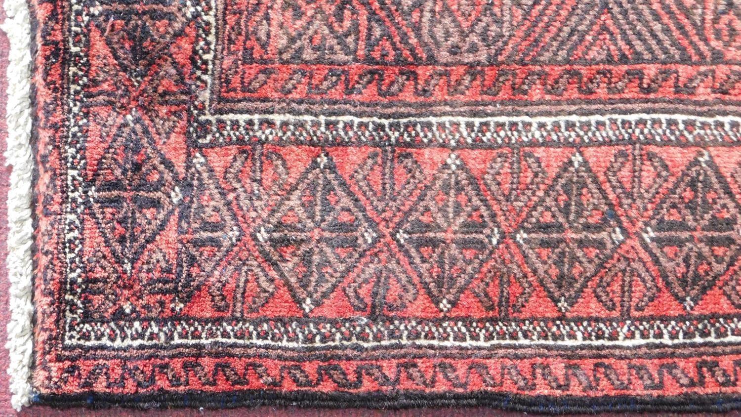 A north east Persian Hatchlie carpet with repeating stylised geometric motifs on a rouge field - Image 2 of 3