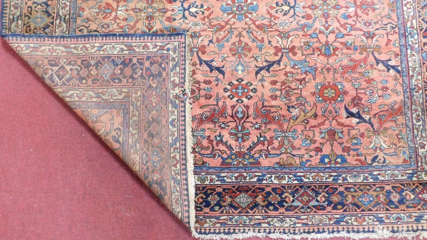 A large Persian rug with repeat motifs on a rouge back ground surrounded by a stylised floral and - Image 3 of 4