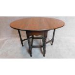 An oak drop flap dining table on bobbin turned supports with a faux rosewood veneered top. H.76 W.