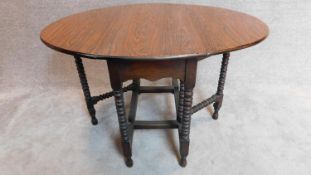 An oak drop flap dining table on bobbin turned supports with a faux rosewood veneered top. H.76 W.