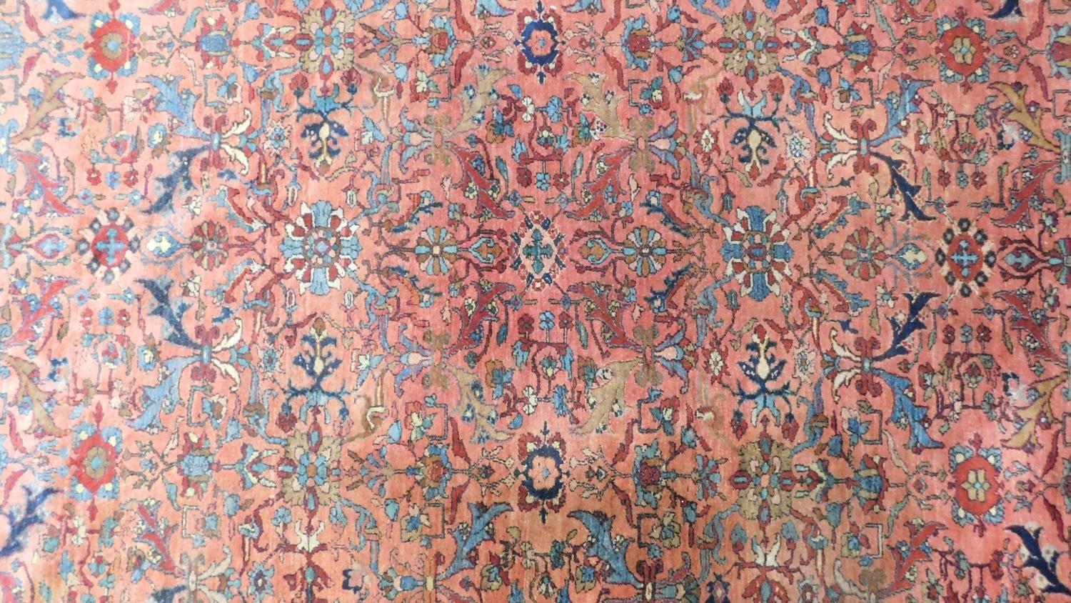 A large Persian rug with repeat motifs on a rouge back ground surrounded by a stylised floral and - Image 4 of 4