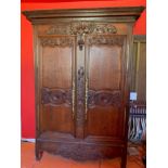 An antique French oak armoire with well carved floral and bouquet decoration fitted ornate brass