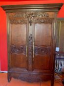 An antique French oak armoire with well carved floral and bouquet decoration fitted ornate brass