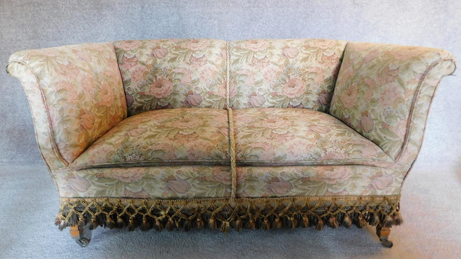 An Edwardian two seater sofa in floral tassled upholstery. 76x137x77cm