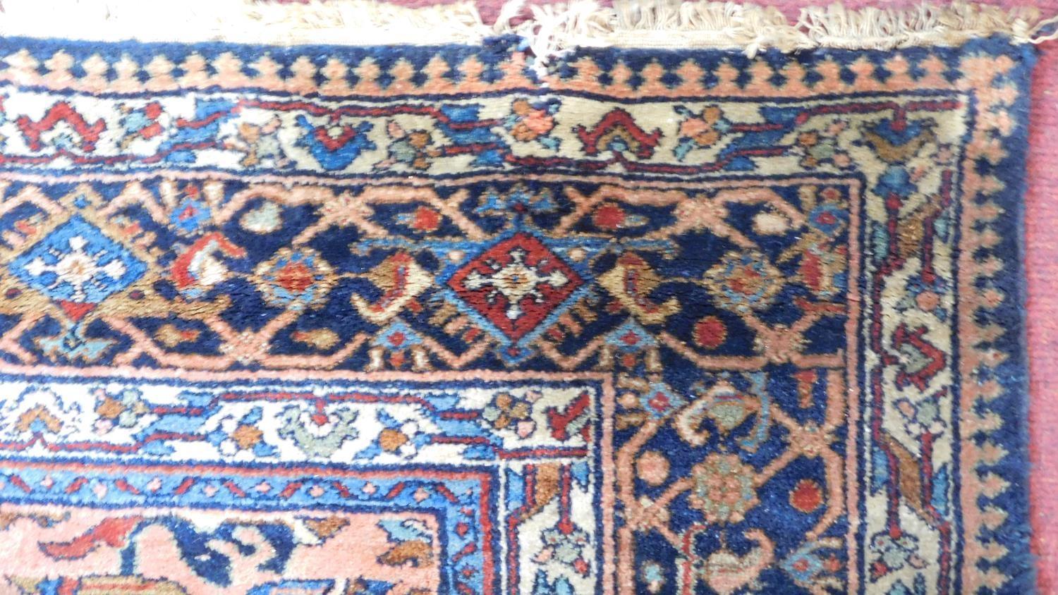 A large Persian rug with repeat motifs on a rouge back ground surrounded by a stylised floral and - Image 2 of 4