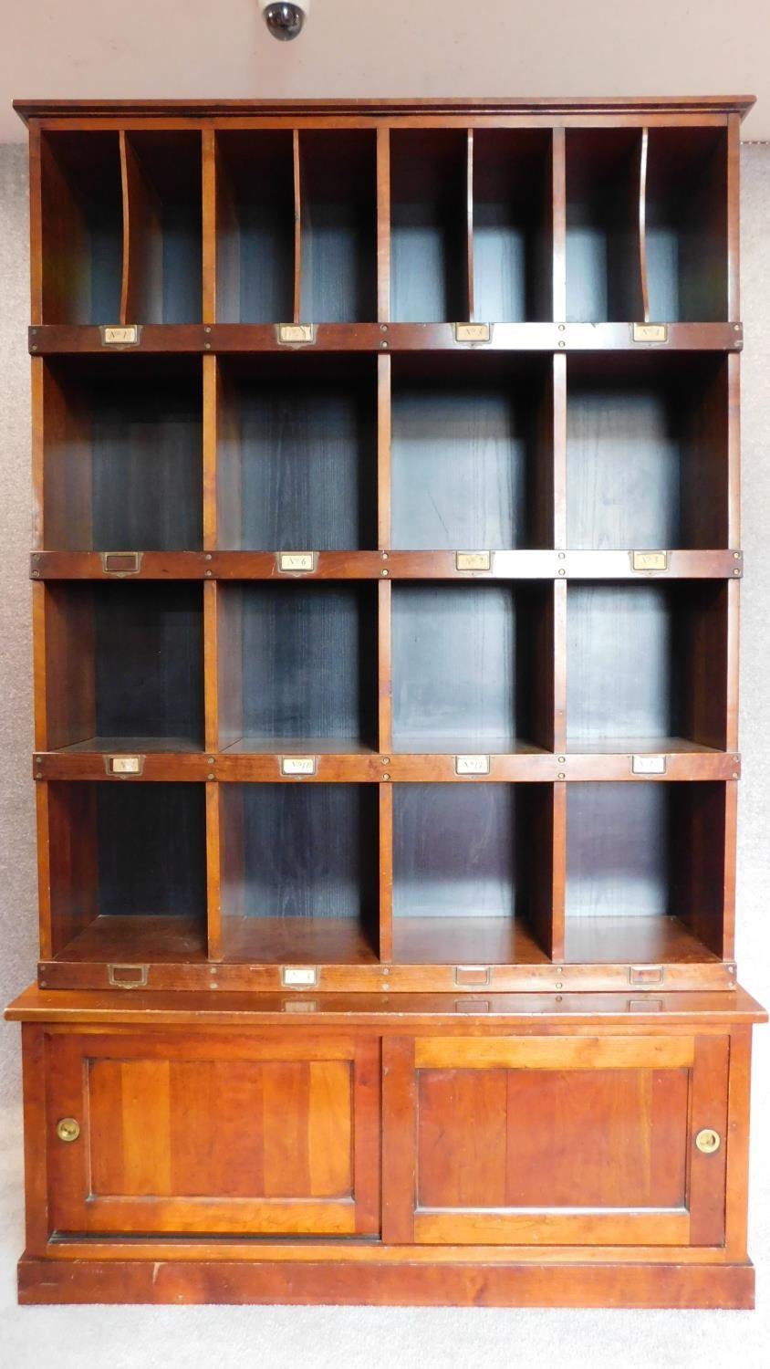 A mahogany two section estate cupboard fitted pigeon holes and stationery sections, makers label