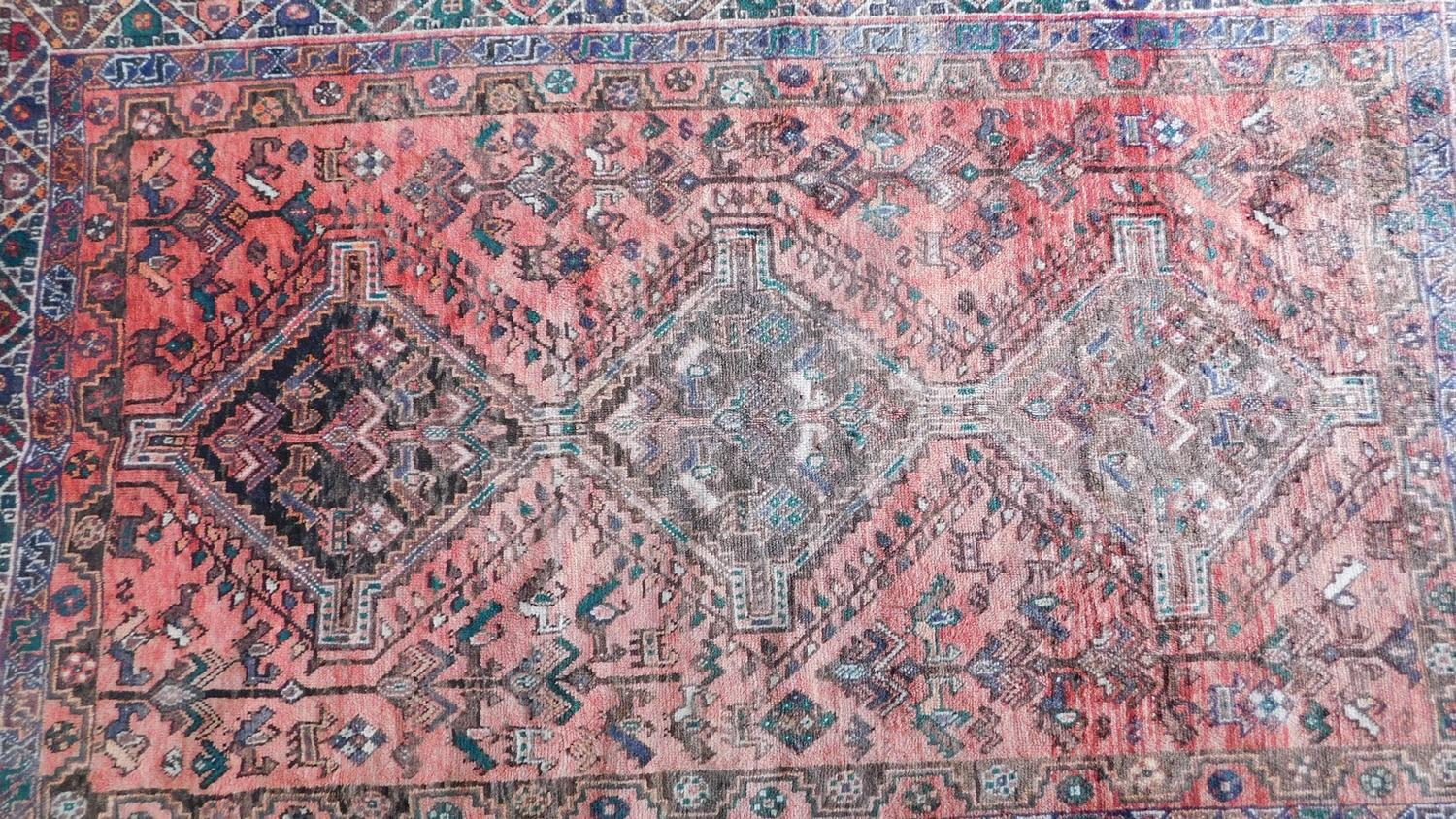 A Persian Qashqai rug with triple pole medallion and repeating geometric motifs on a terracotta - Image 4 of 4