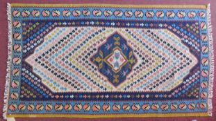 A Qashgai Kelim rug with central pole medallion and repeating geometric motifs on an ivory field.