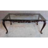 A Continental style mahogany dining table with shaped plate glass top on cabriole supports.