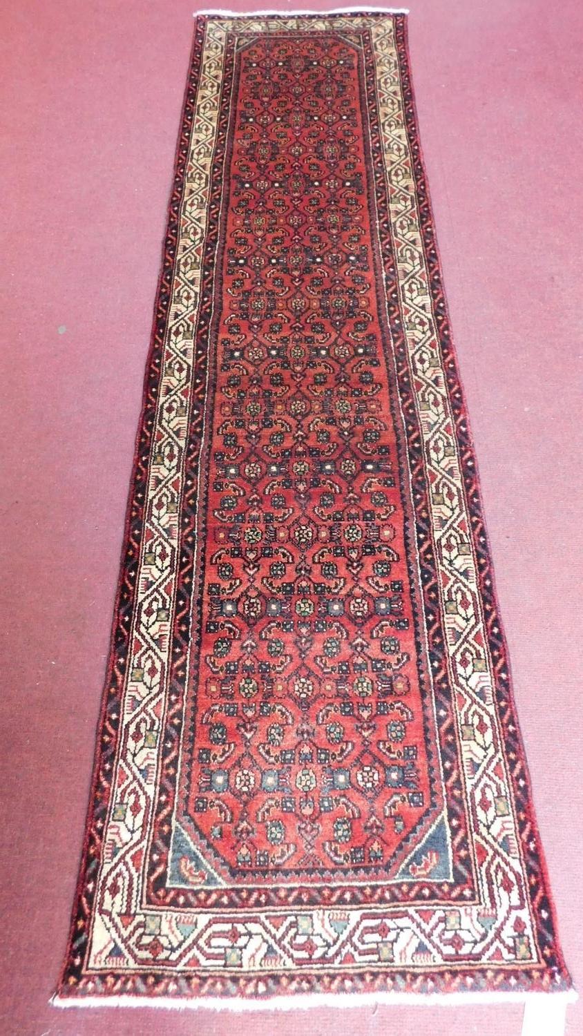 A Persian Malayer runner, repeating heratie motifs on a terracotta field within stylised multifloral