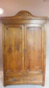 A 19th century Continental chestnut armoire with carved pediment and panel doors above base fitted