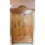 A 19th century Continental chestnut armoire with carved pediment and panel doors above base fitted